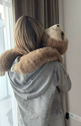 Avis client d’une adulte portant une peluche lestée paresseux près de la fenêtre
